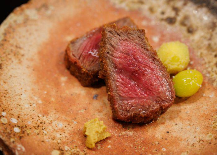 A medium-rare serving of wagyu beef on a rustic serving plate at Nikunotakumi Miyoshi.